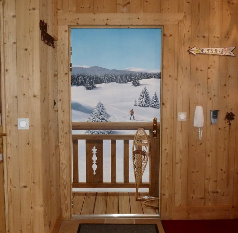 Trompe-l'oeil réalisé sur une porte d'entrée. Il représente un paysage enneigé avec barrière en bois