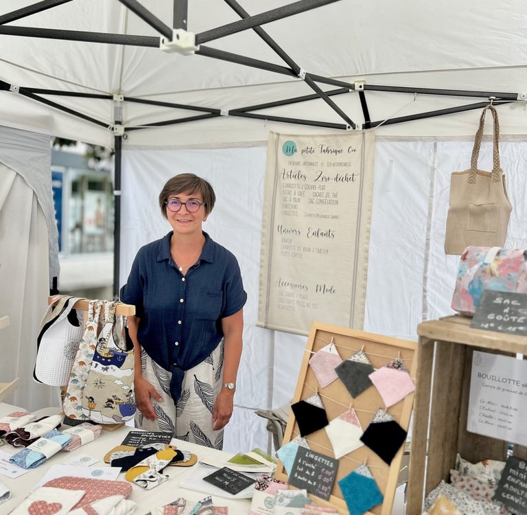 La créatrice derrière son stand sur un marché de créations artisanales