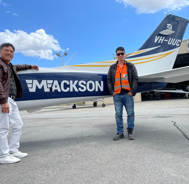 a man standing next to a plane with a man in a vest