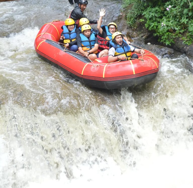 Sekelompok orang di atas perahu karet merah sedang berarung jeram menuruni jeram sungai.