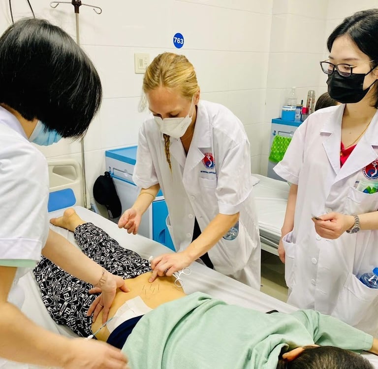 Professional practitioners perform acupuncture therapy on a patient's lower back in a clinical setting.