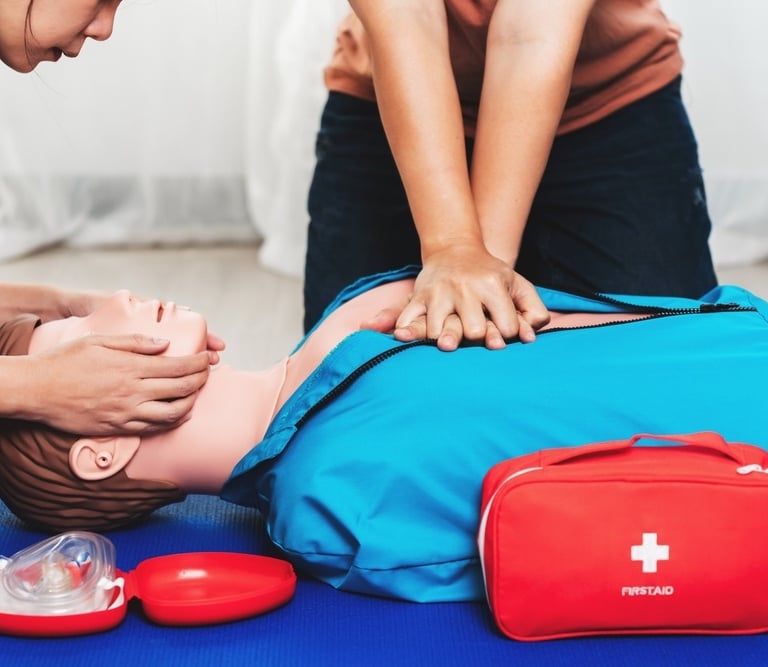 Two people practising CPR on a dummy in First Aid training