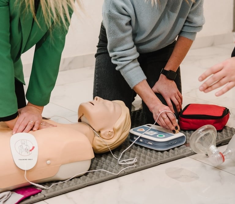 Two women administering CPR training on a CPR dummy in a training
