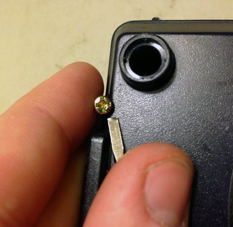 a person holding a small piece of metal with a small screwr