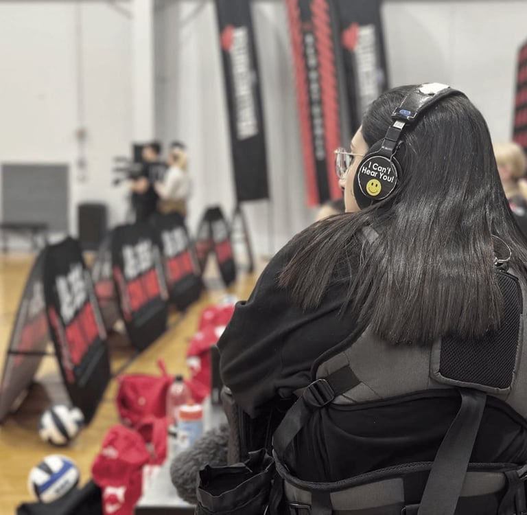 a woman in a black jacket and headphones on a basketball court