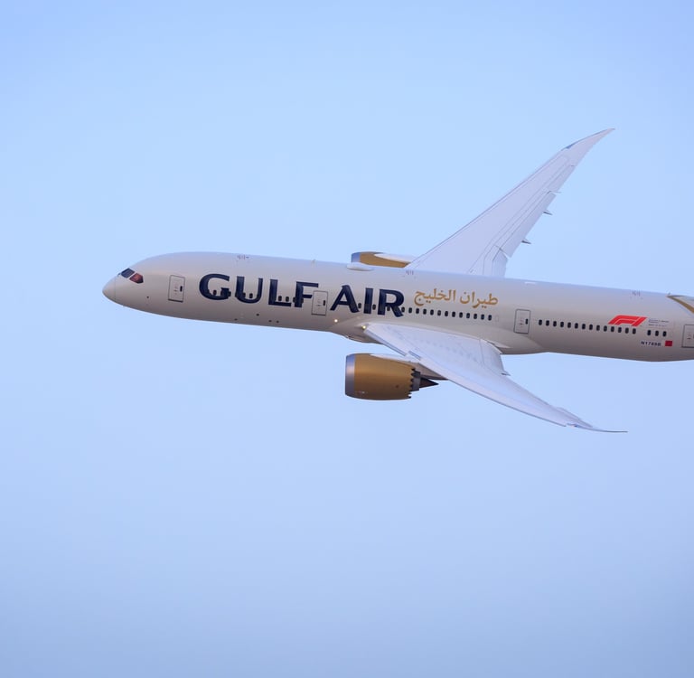 A white Gulf Air Boeing 787-9 Dreamliner passenger jet flying through a clear blue sky.