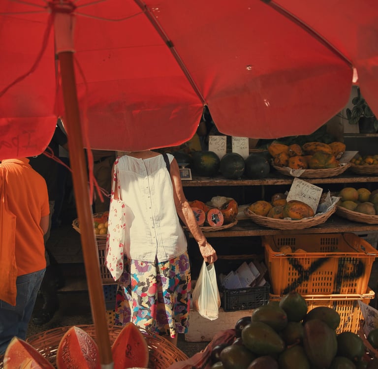 Street market scene under red umbrella showing fruit vendors and shoppers at Port Louis Central Market, Mauritius