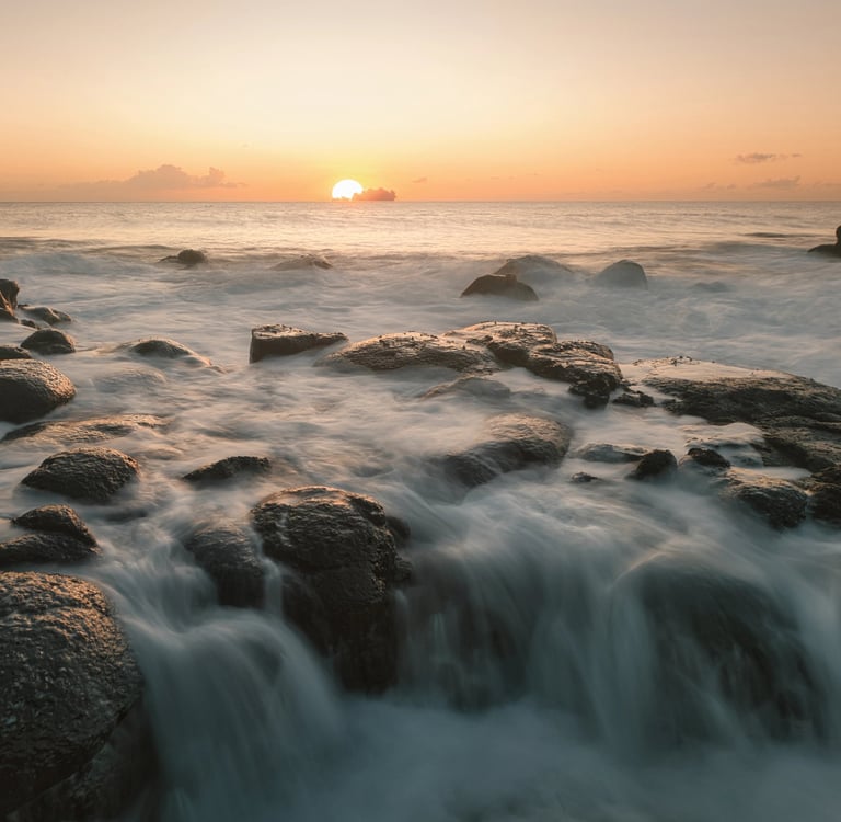 Sunrise over ocean waves on rocky shores in Albion, Mauritius