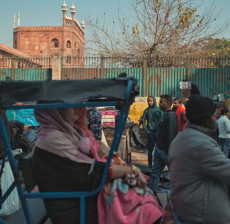 Crowded Old Delhi street with rickshaws and pedestrians near Jama Masjid.