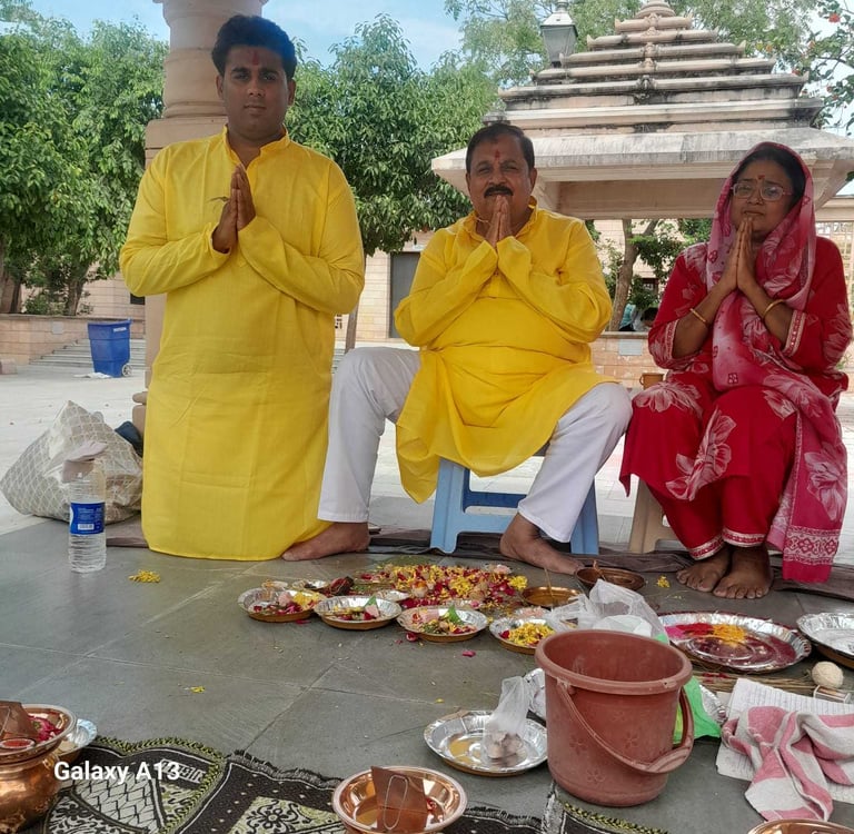 Father and son in yellow kurtas with wife in a red saree performing Matrugaya Pooja — Bindu Sarovar,
