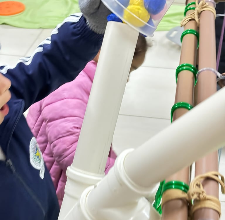 Criança brincado com bolinhas coloridas em canos.