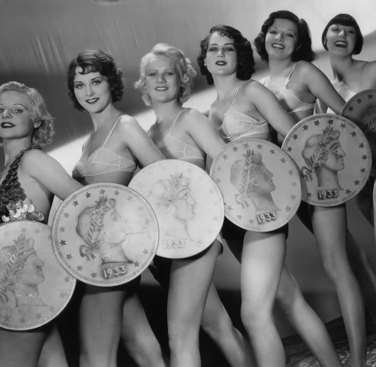 Low‑angle shot of Gold Diggers of 1933 chorus girls holding giant coins in “We’re in the Money.”