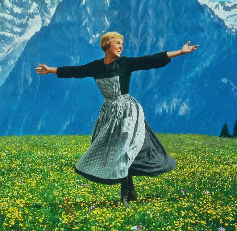 Julie Andrews as Maria stands arms wide on a mountain in The Sound of Music