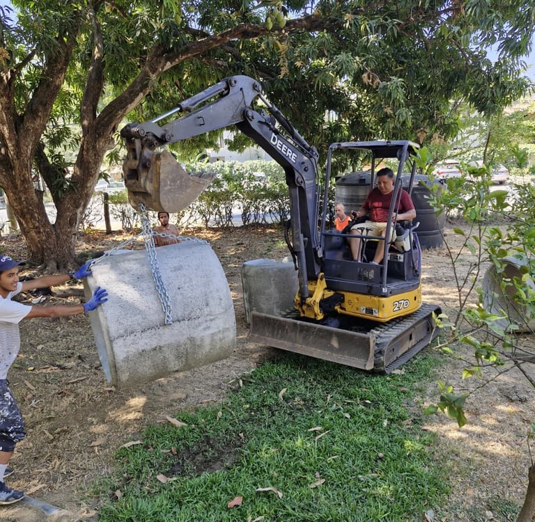 Mini excavator moving concrete septic pipes