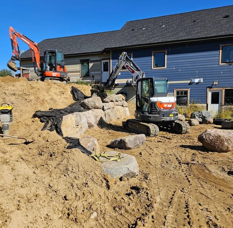Excavators building boulder wall at residential home in cokato mn