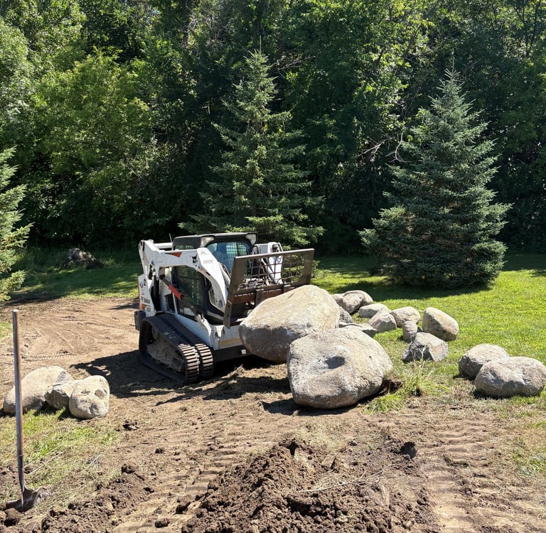 Bobcat skid steer hauling large boulders
