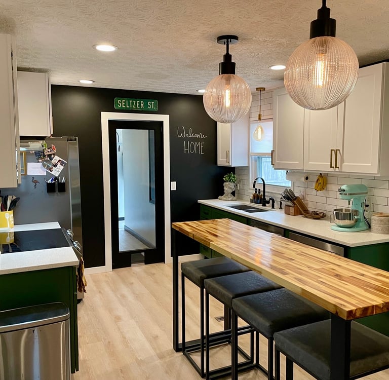 Modern kitchen with green cabinets, butcher block island, and globe pendant lighting.