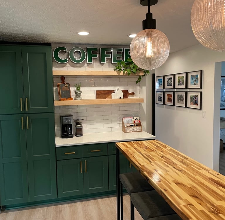 Modern home coffee station with green cabinets, butcher block table, and globe pendant lighting.