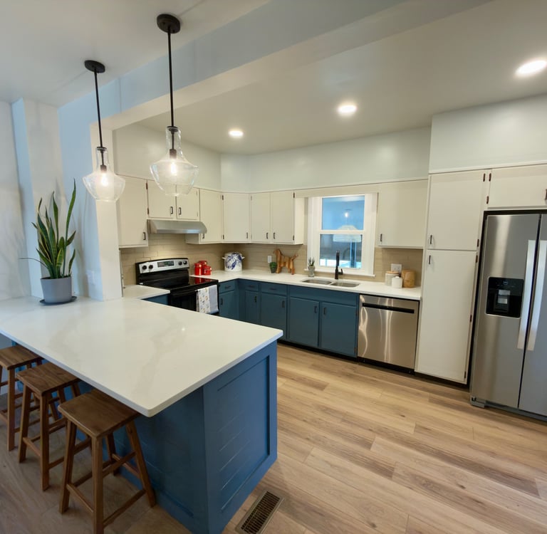 Modern kitchen with blue lower cabinets, white upper cabinets, a waterfall island, and stainless steel appliances.