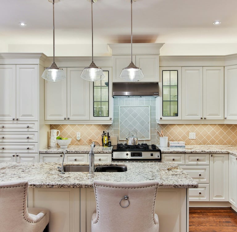 Luxury pastel and white tone kitchen. Light granite benchtops and a steel refrigerator.