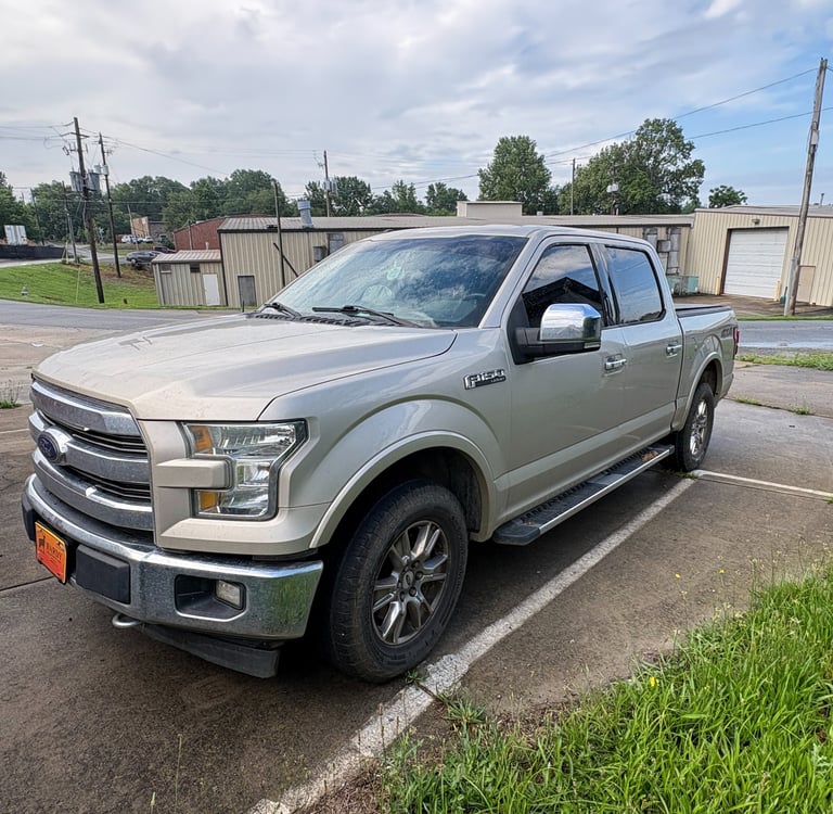A gold F-150 Lariat pickup truck parked in an industrial lot.
