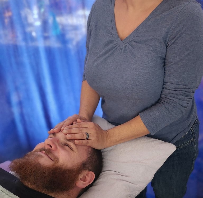Professional practitioner performing a relaxing Reiki energy healing session on a man's forehead.