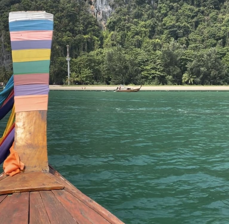 Ein traditionelles thailändisches Longtail-Boot auf türkisfarbenem Wasser nahe üppigen tropischen.