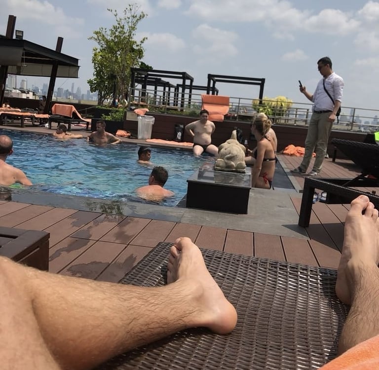 Gäste entspannen am Rooftop-Pool eines Luxushotels mit Blick auf die Skyline und Sonnenliegen