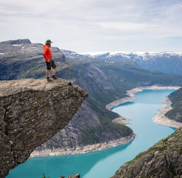 a photo of troltunga mountain in norway with a gree lake
