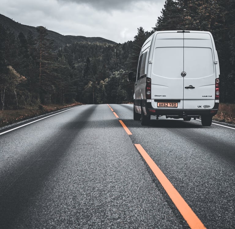 photo of camper van driving through forest in Norway