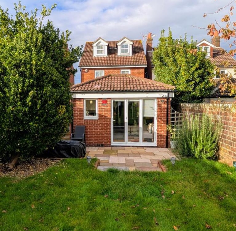 modern rear extension, stone patio, and green lawn garden.