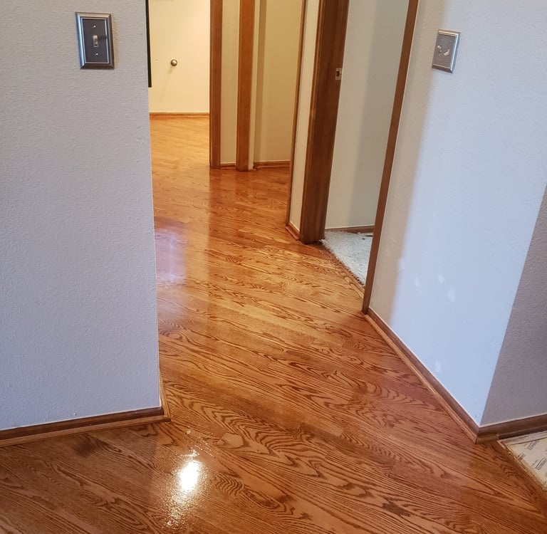 Polished red oak hardwood flooring with a glossy finish in a home hallway and entrance.