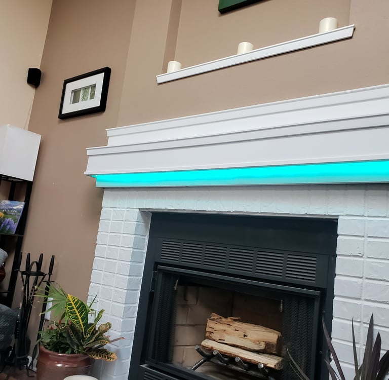 Modern white brick fireplace featuring a turquoise LED light strip under the mantel in a cozy living room.