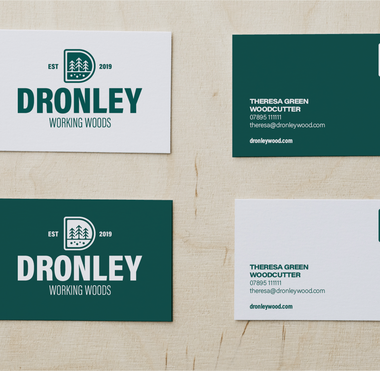 Custom woodcutter business cards for Dronley Working Woods featuring forest-themed branding on light wood.