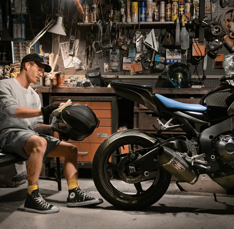 man cleaning his motorcycle helmet next to his motorcycle