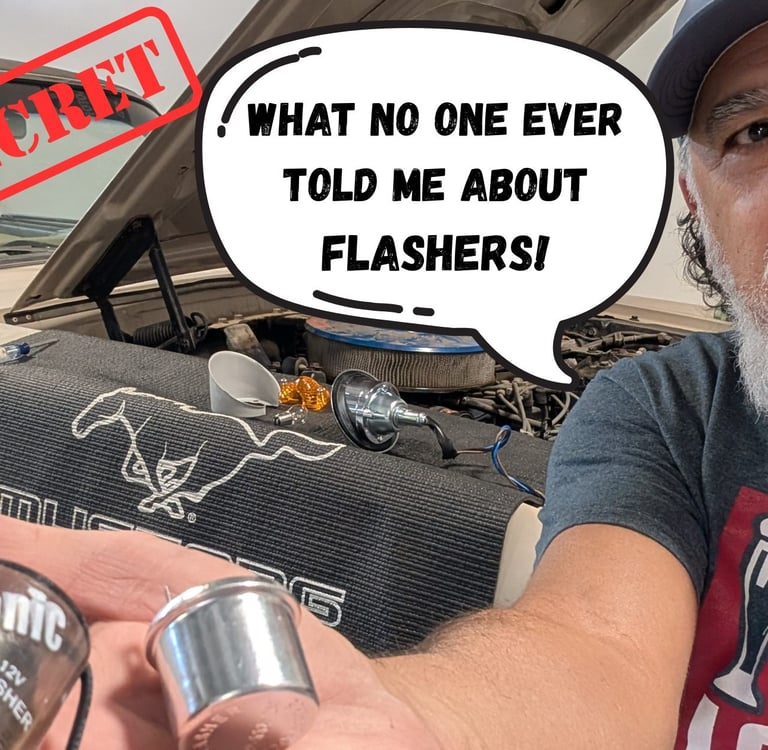 A mechanic holding a 12V car flasher relay in front of a classic Ford Mustang engine bay.