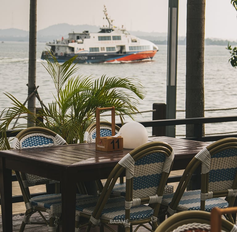 an outdoor area looking at the seaside with ferry passing by at SeeSea by Nomad Batam