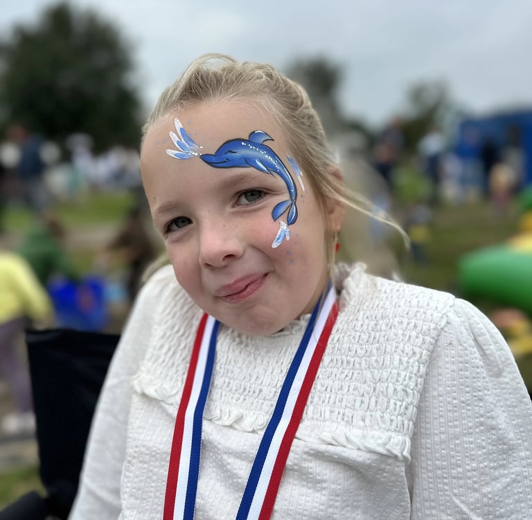 Meisje met een gedetailleerde blauwe dolfijn op haar gezicht geschminkt.