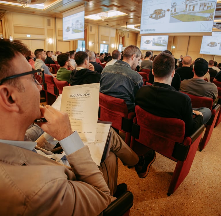 Professional audience attending a business seminar with architectural presentations on overhead screens.