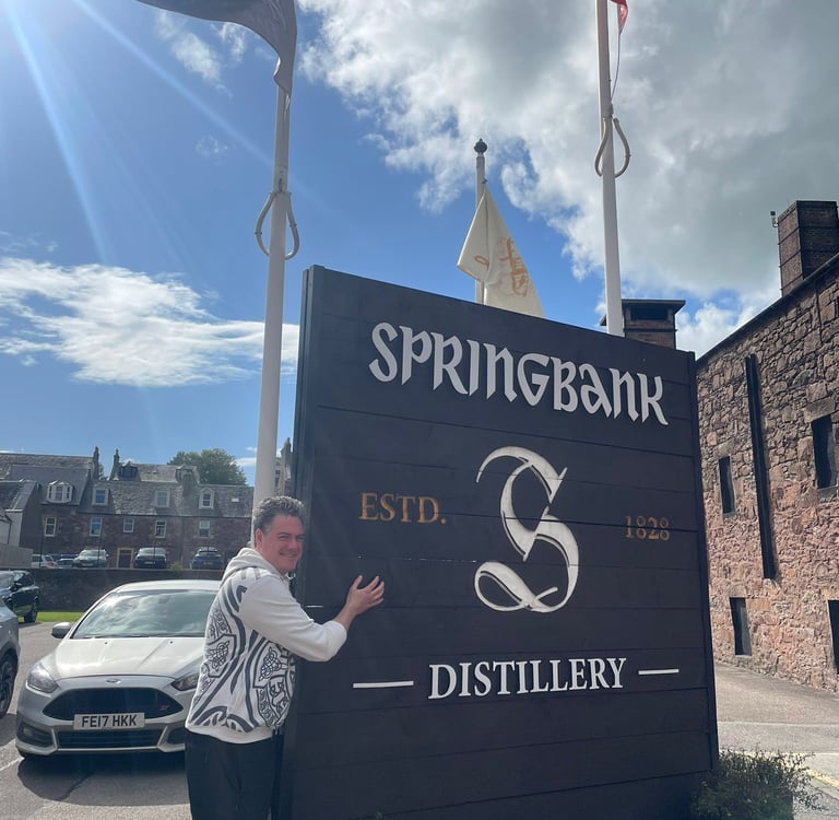 Chef Greg hugging sign at Springbank distillery