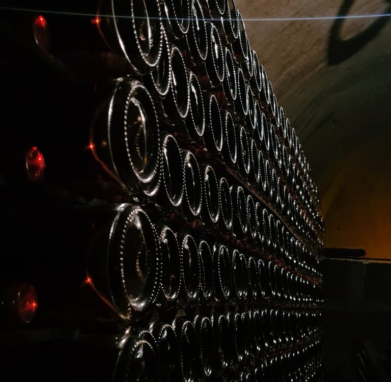 Atmospheric view of champagne bottles aging in a historic underground cellar, captured in dramatic low light.