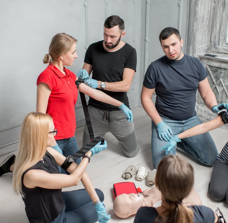 People sitting in a classroom learning how to apply a tourniquet