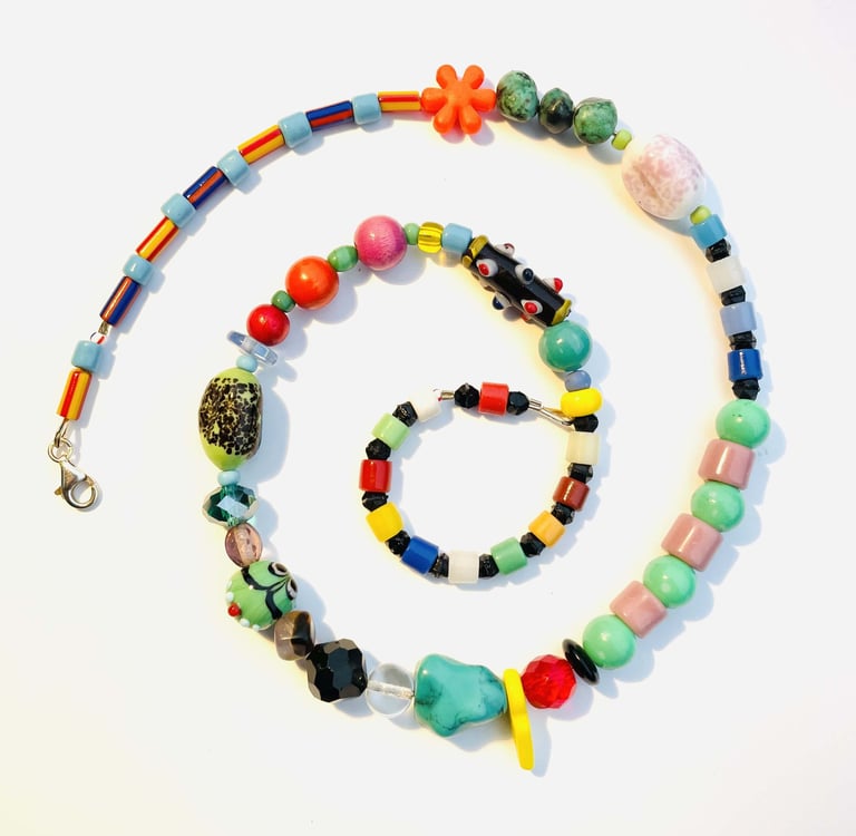 Handmade colorful beaded necklace spiral with eclectic glass and ceramic beads on white background.
