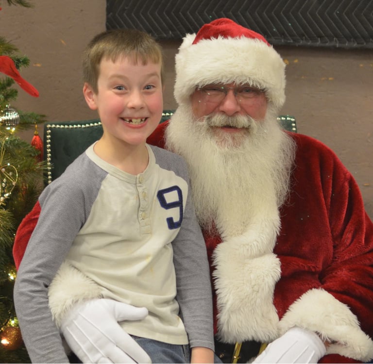 Santa Tom with smiling boy sitting on knee