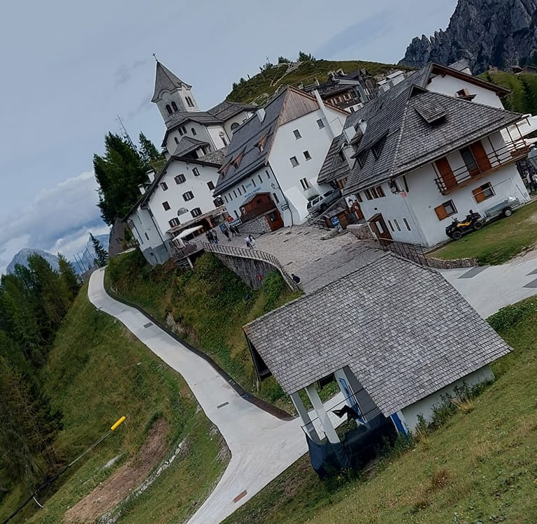 Charming alpine village of Monte Lussari in the Julian Alps with traditional white buildings and a church.