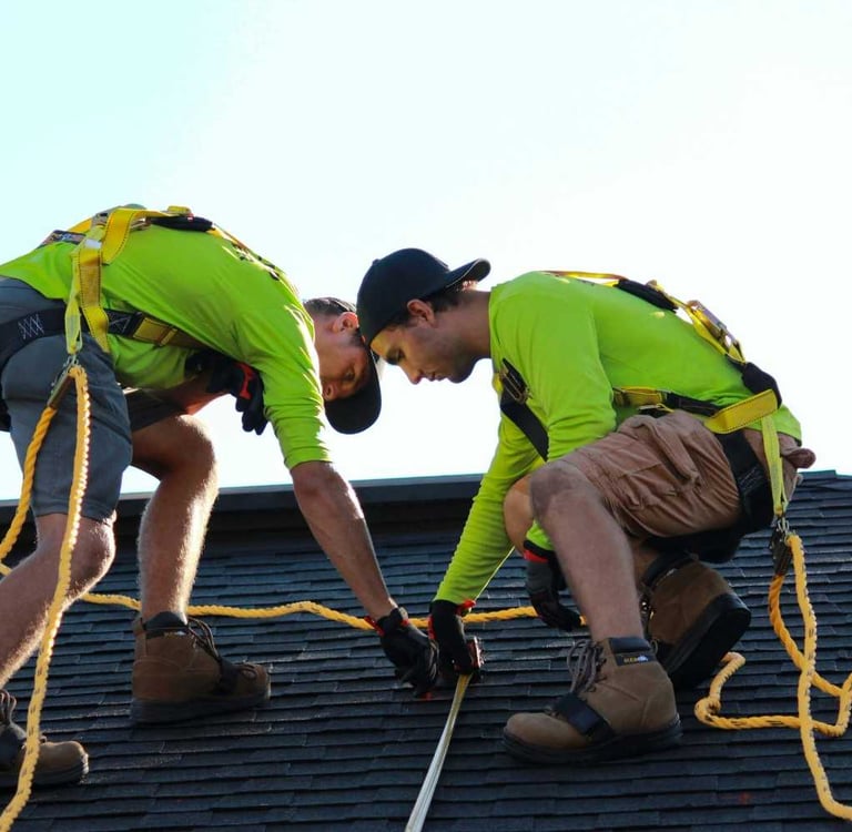 Roofing contractors replacing shingles on a Colorado Springs home with mountain views in the background