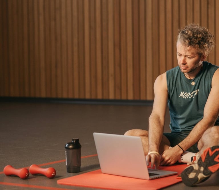 a man sitting on a mat with a laptop computer