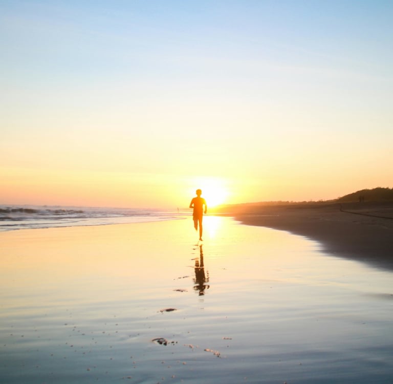 a person walking on a beach at sunset
