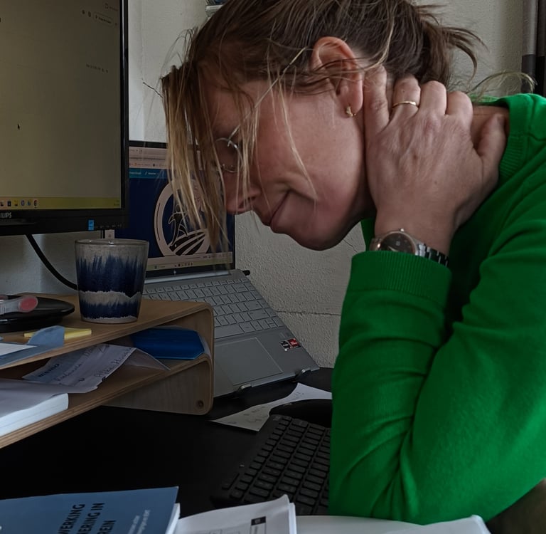 Woman experiencing neck pain while working on a laptop at her office desk.