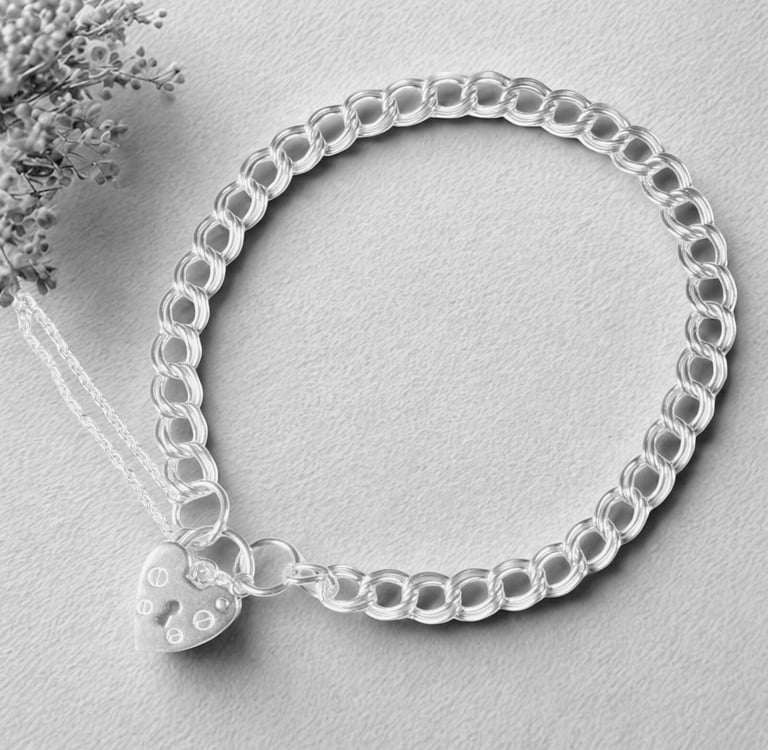 Sterling silver charm bracelet with a heart-shaped padlock clasp on a textured grey background.